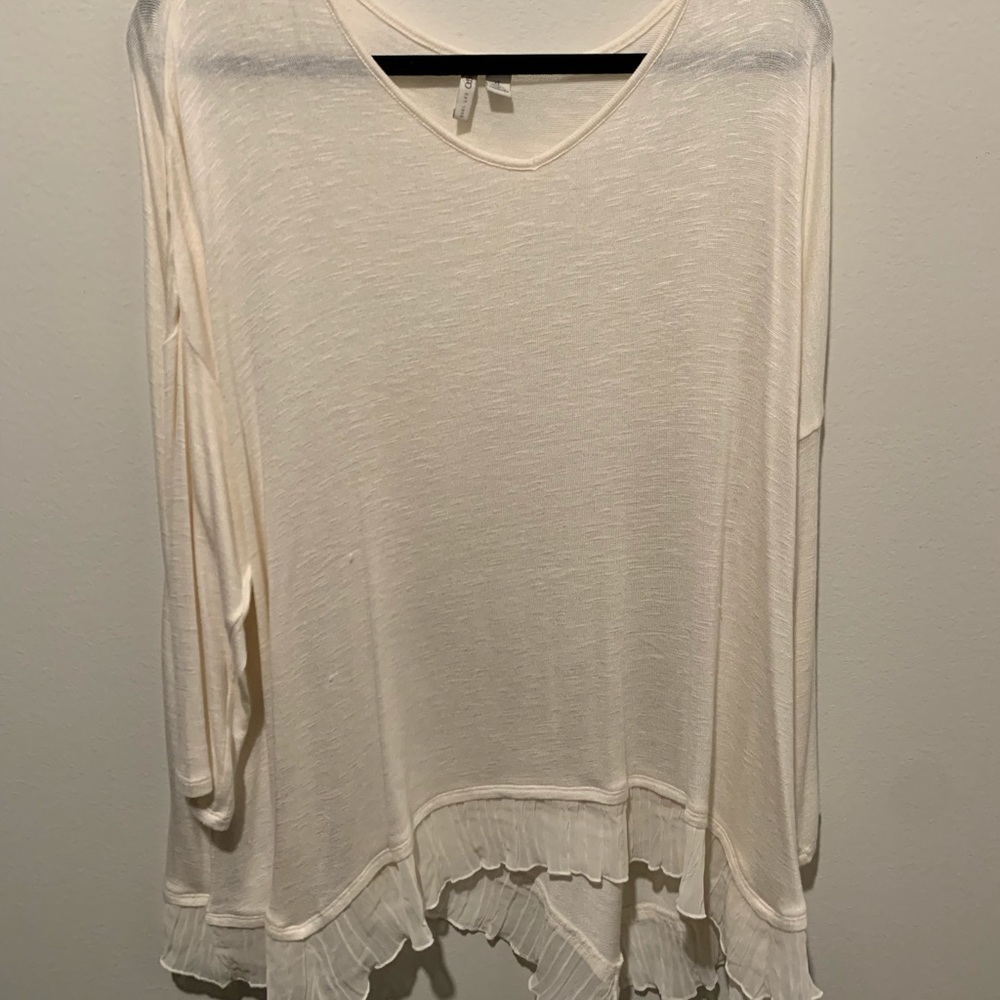 Cream-colored, sheer white blouse with ruffling